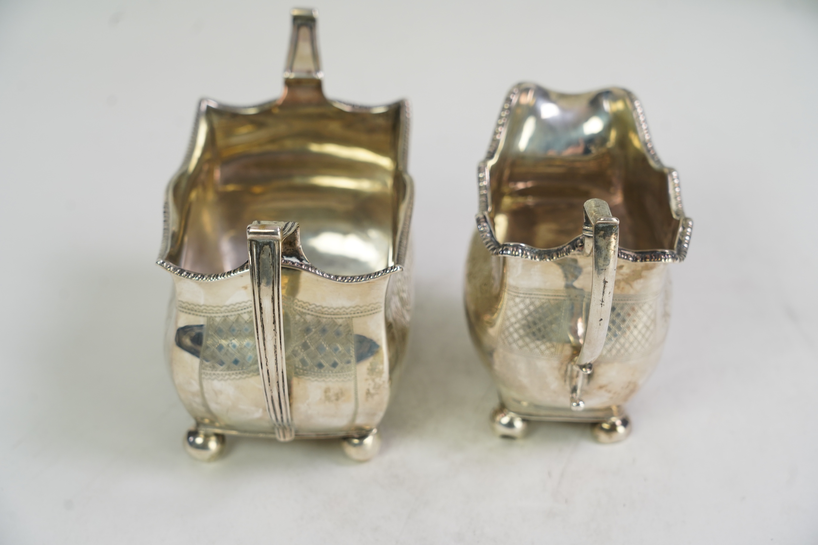 A George III Irish silver two handled sugar bowl, by Richard Sawyer, Dublin, 1808, 18.4cm over handles, with engraved armorial, on four ball feet, together with a similar cream jug, by Daniel Egan, Dublin, 1811, 16.2oz.